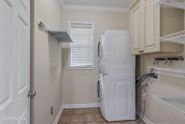 washroom featuring crown molding, stacked washer and dryer, light tile patterned floors, and cabinets