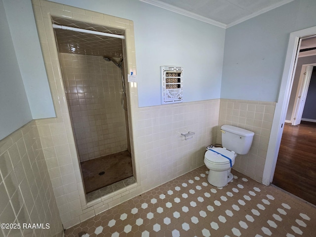 bathroom with toilet, a tile shower, crown molding, and tile walls