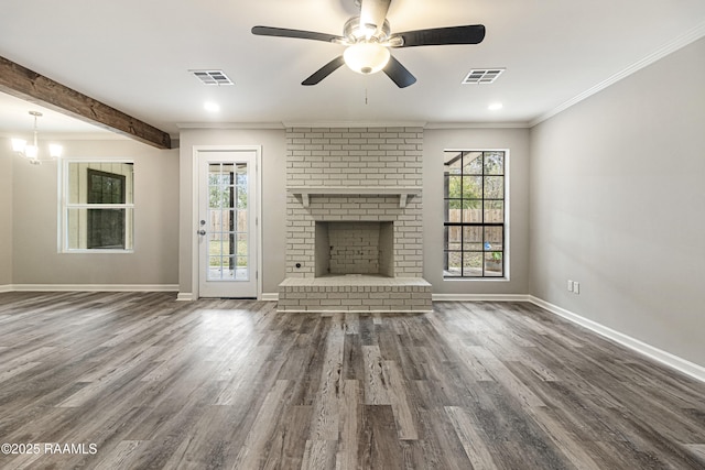 unfurnished living room with dark wood-type flooring, ornamental molding, a healthy amount of sunlight, and a brick fireplace