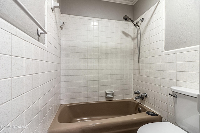 bathroom with tile walls, tiled shower / bath combo, and toilet