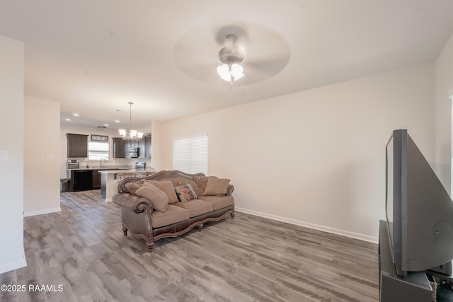 living room featuring hardwood / wood-style flooring, ceiling fan with notable chandelier, and sink