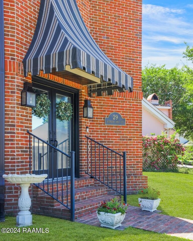 property entrance with a lawn and french doors