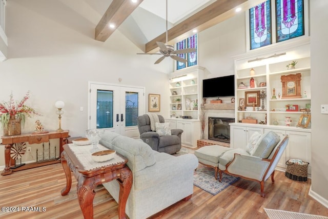 living room featuring ceiling fan, french doors, a high ceiling, beamed ceiling, and light wood-type flooring