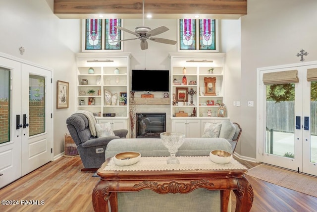 living room with ceiling fan, beam ceiling, light wood-type flooring, and french doors