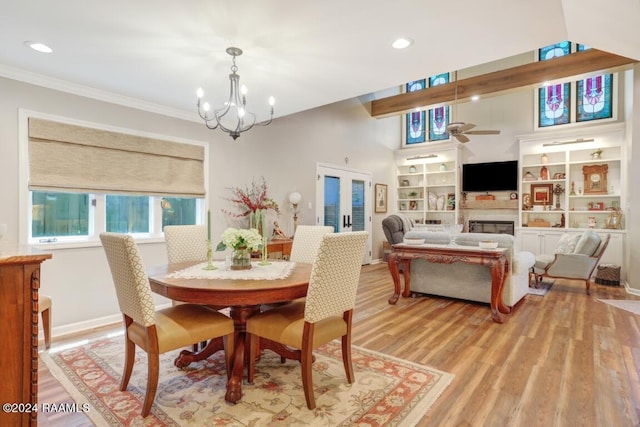 dining room featuring built in shelves, french doors, an inviting chandelier, light hardwood / wood-style flooring, and ornamental molding