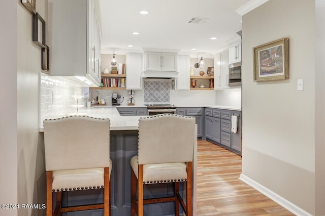 kitchen with stainless steel electric range, a kitchen bar, kitchen peninsula, and backsplash