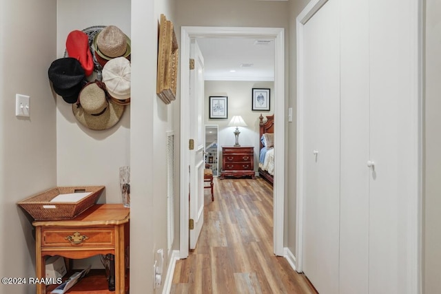 corridor with light hardwood / wood-style floors and crown molding