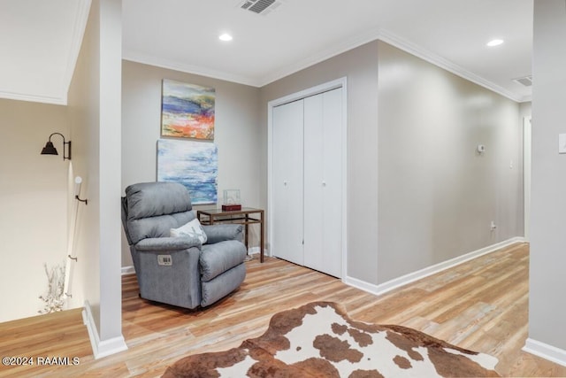 living area featuring light hardwood / wood-style floors and crown molding