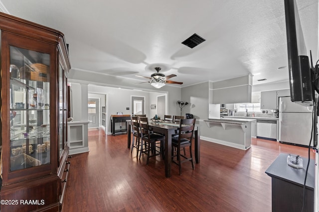 dining area with a textured ceiling, ceiling fan, crown molding, and dark hardwood / wood-style floors