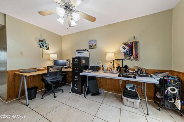 tiled office space featuring wood walls and ceiling fan