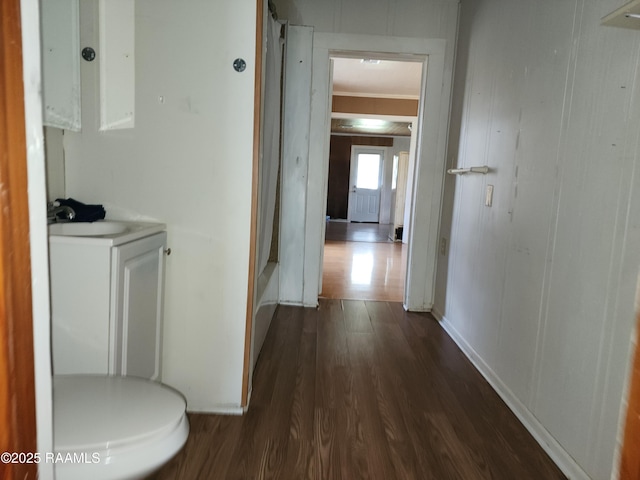 hall with dark wood-style floors, baseboards, ornamental molding, and a sink