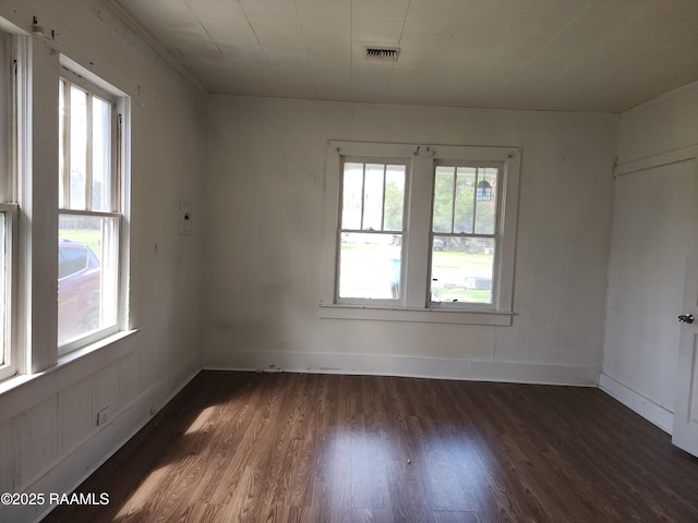 empty room featuring baseboards, visible vents, and wood finished floors