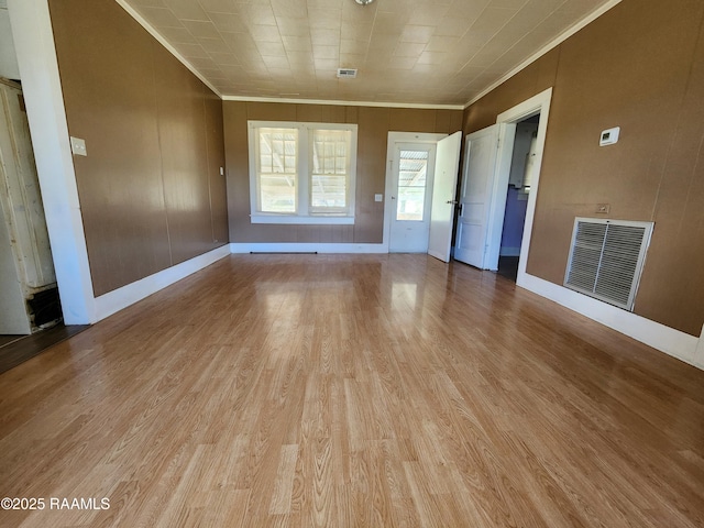 unfurnished room featuring baseboards, wood finished floors, visible vents, and crown molding