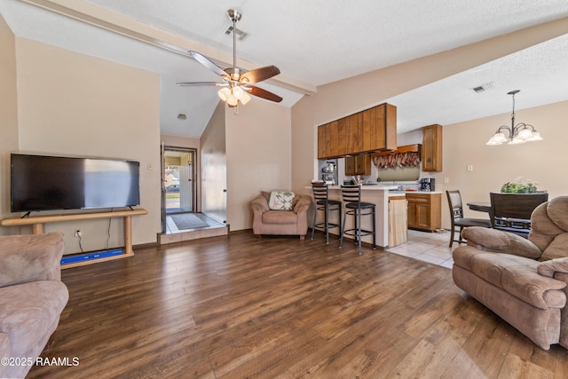 living room with ceiling fan with notable chandelier, light hardwood / wood-style floors, a textured ceiling, and vaulted ceiling