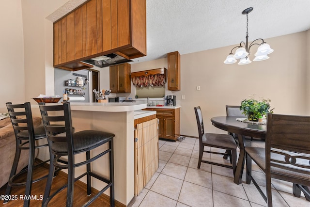 kitchen with an inviting chandelier, a kitchen breakfast bar, decorative light fixtures, light tile patterned flooring, and kitchen peninsula