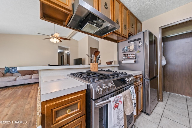 kitchen featuring gas range, a textured ceiling, ceiling fan, range hood, and light tile patterned flooring