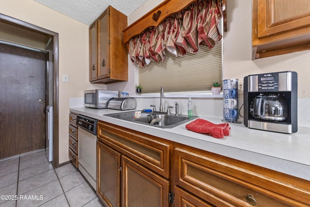 kitchen featuring a textured ceiling, light tile patterned floors, sink, and appliances with stainless steel finishes