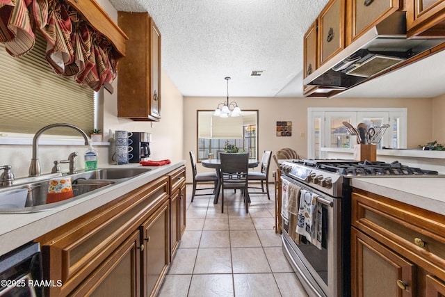 kitchen featuring high end range, a textured ceiling, sink, an inviting chandelier, and hanging light fixtures