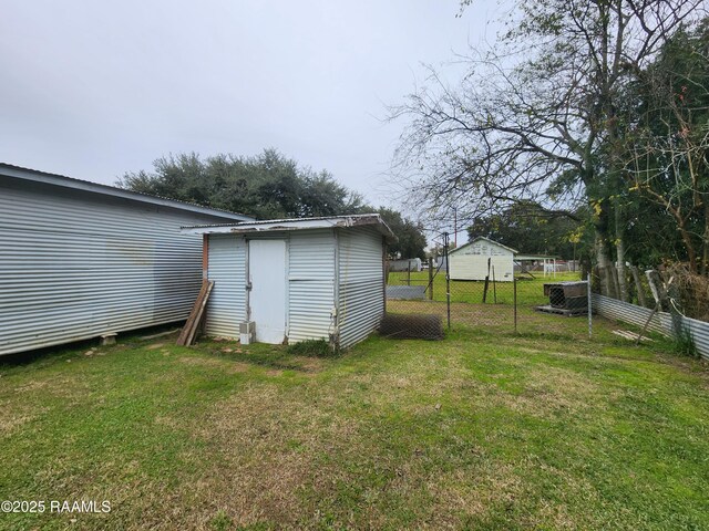 view of yard featuring a storage shed, fence, and an outdoor structure