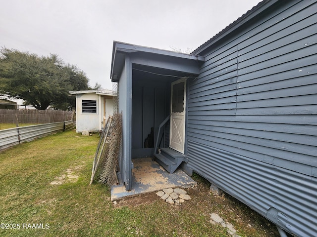 view of exterior entry with a yard and fence