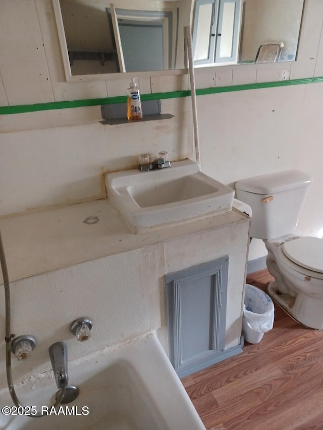 bathroom with toilet, decorative backsplash, wood finished floors, and vanity