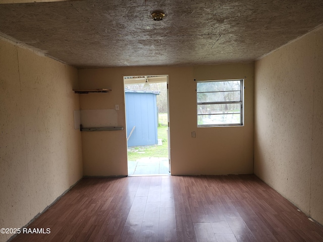 unfurnished room with a textured wall and wood finished floors