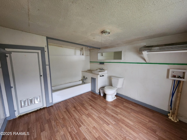 bathroom featuring visible vents, toilet, a sink, a textured ceiling, and wood finished floors