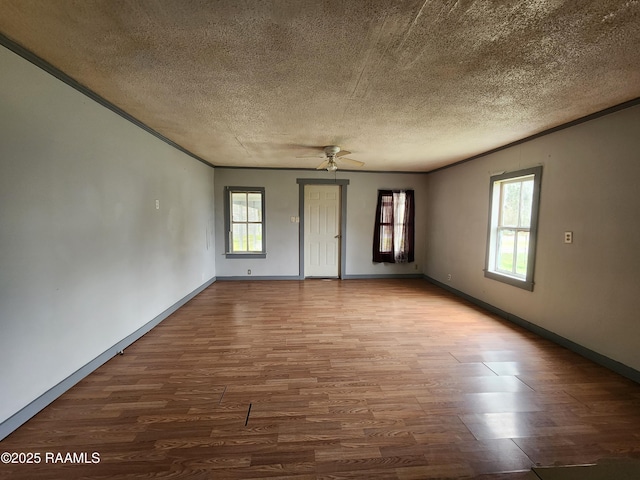 empty room featuring ornamental molding, a textured ceiling, baseboards, and wood finished floors