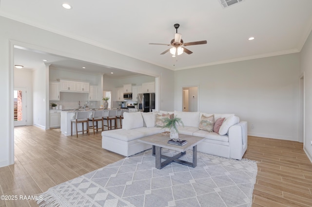 living room with ceiling fan, light hardwood / wood-style floors, sink, and crown molding