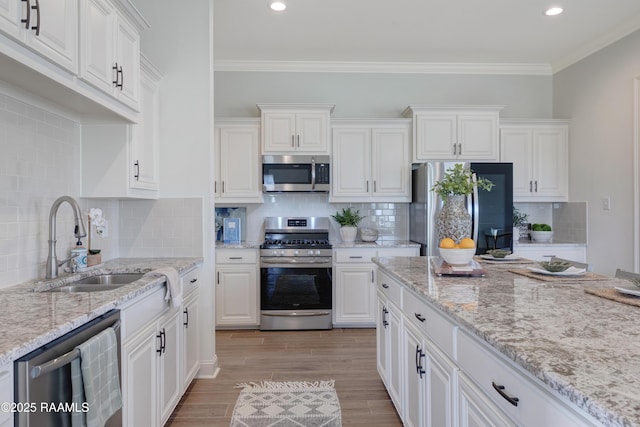 kitchen featuring white cabinetry, sink, stainless steel appliances, light stone counters, and crown molding