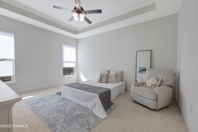 bedroom featuring a raised ceiling, ceiling fan, crown molding, and light colored carpet