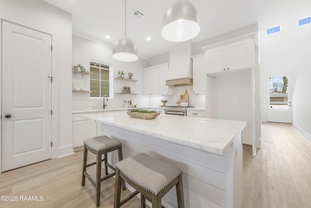 kitchen with a center island, white cabinetry, and custom exhaust hood