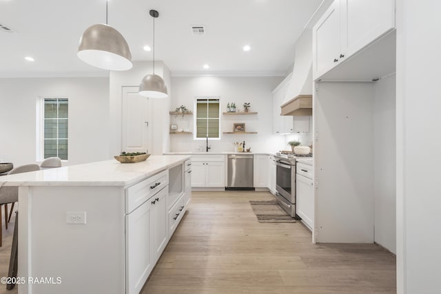 kitchen featuring pendant lighting, a center island, white cabinets, light hardwood / wood-style floors, and stainless steel appliances