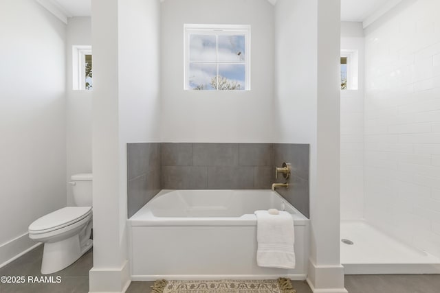 bathroom with tile patterned floors, toilet, a healthy amount of sunlight, and a tub