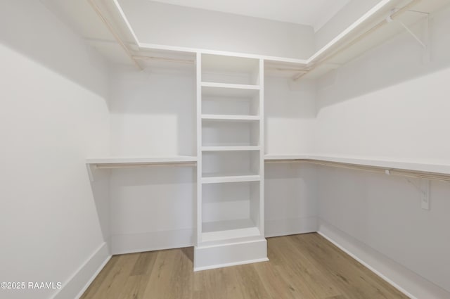 walk in closet with light hardwood / wood-style flooring