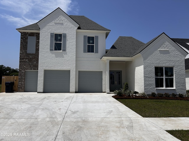 view of front of property featuring a front yard, fence, brick siding, a garage, and driveway