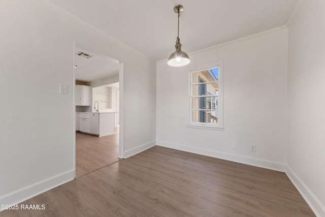 unfurnished dining area featuring built in shelves, crown molding, sink, and dark wood-type flooring