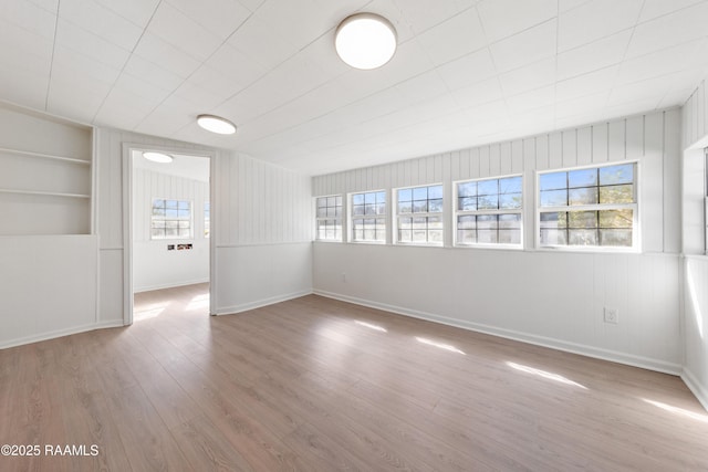 empty room featuring hardwood / wood-style floors, built in shelves, and plenty of natural light