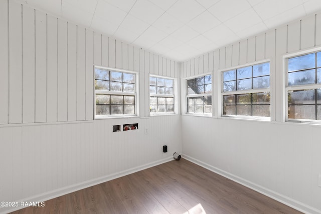 clothes washing area with hardwood / wood-style floors, washer hookup, and wood walls