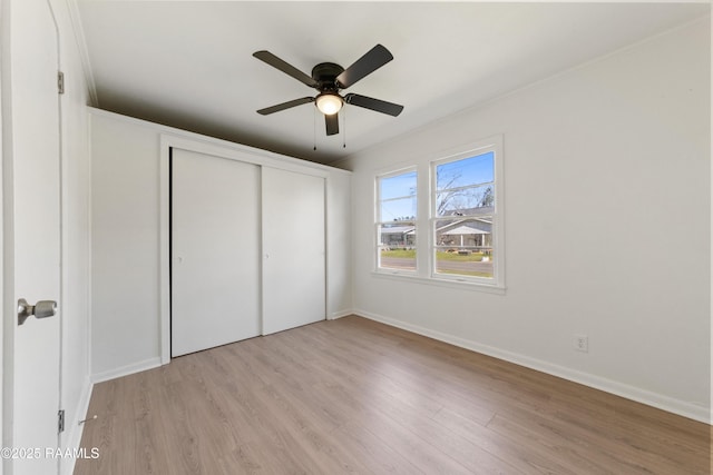 unfurnished bedroom with light wood-type flooring, a closet, ceiling fan, and crown molding