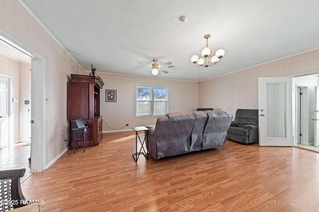 living room with ceiling fan with notable chandelier, ornamental molding, and light hardwood / wood-style floors