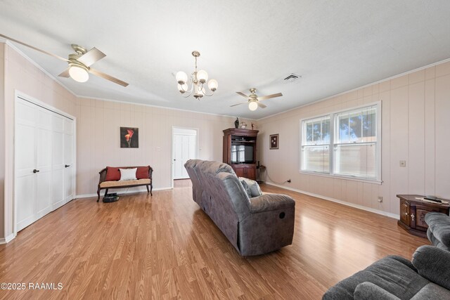 living room featuring ornamental molding, ceiling fan with notable chandelier, and light wood-type flooring