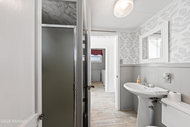 bathroom with wood-type flooring, toilet, and a shower with door