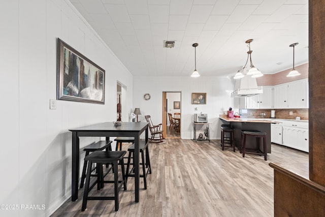 dining space featuring ornamental molding and light hardwood / wood-style floors