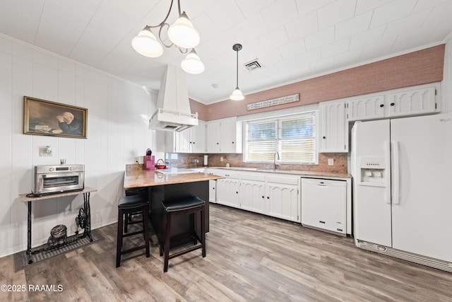 kitchen with custom exhaust hood, hanging light fixtures, a kitchen breakfast bar, white appliances, and white cabinets