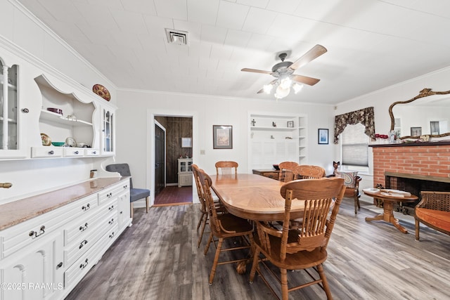 dining area with a brick fireplace, dark wood-type flooring, and ornamental molding