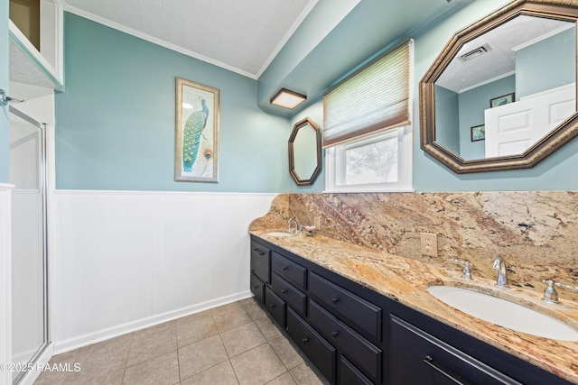 bathroom featuring tile patterned floors, ornamental molding, a shower with door, and vanity