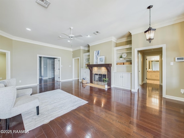 living room featuring crown molding, ceiling fan, dark hardwood / wood-style floors, and built in shelves