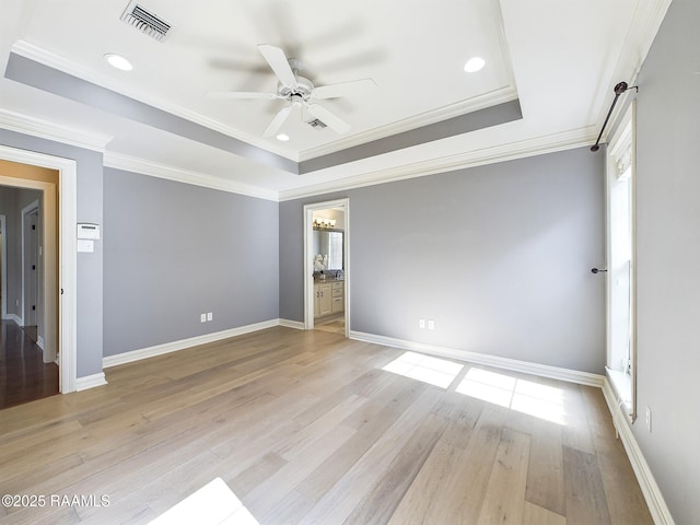 spare room featuring ornamental molding, ceiling fan, light hardwood / wood-style floors, and a tray ceiling