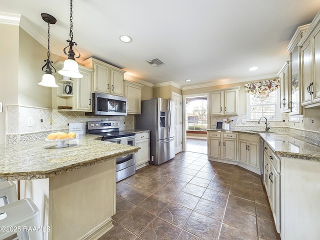 kitchen with hanging light fixtures, stainless steel appliances, ornamental molding, light stone countertops, and a kitchen bar